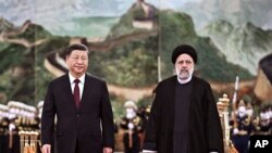 Iranian President Ebrahim Raisi, right, walks with Chinese President Xi Jinping 