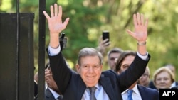 Venezuelan opposition leader Edmundo Gonzalez Urrutia (Front) waves to supporters next to Uruguay's President Luis Lacalle Pou after a meeting at the Suarez and Reyes presidential residence in Montevideo on January 4, 2025.