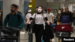 Viajeros con mascarillas provenientes de Europa llegan al aeropuerto de Sao Paulo, en Brasil, donde se repotó el primer caso de coronavirus en América Latina el 26 de febrero de 2020.